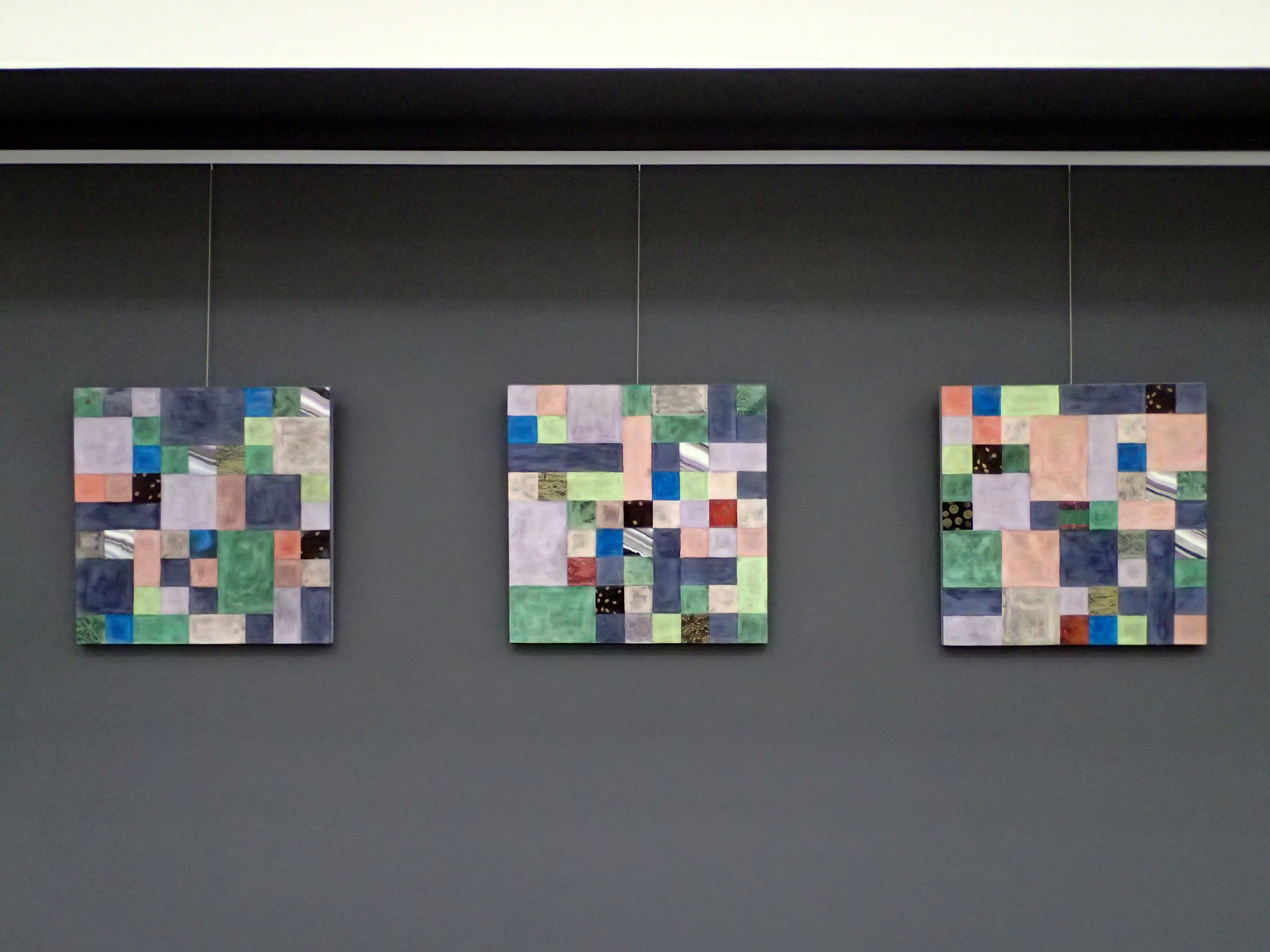 Triptych Painting shown on a black wall.